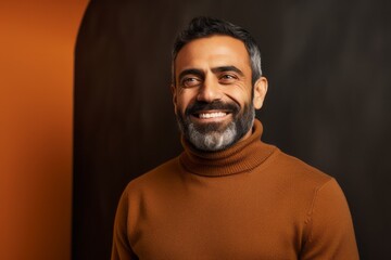 Obraz premium smiling indian man in brown sweater looking at camera isolated on black