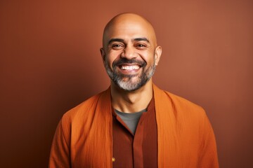 Fototapeta premium Portrait of a happy middle-aged Indian man on brown background