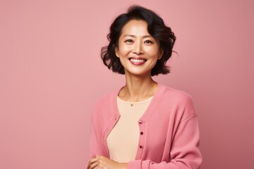 Obraz premium Portrait of a smiling asian woman looking at camera isolated over pink background