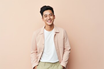 Handsome young asian man smiling and looking at camera isolated over beige background
