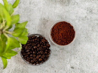 Top close up shot of roasted beans, coffee powder with defocused tree leaves.