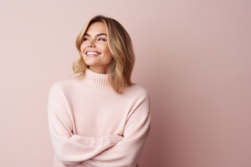 Fototapeta premium Portrait of a beautiful young woman in a pink sweater on a pink background