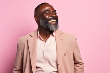 Obraz premium Portrait of happy african american man in beige suit laughing and looking at camera on pink background