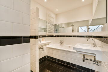 a bathroom with black and white tiles on the walls, sink and mirror in the background is an open shower stall