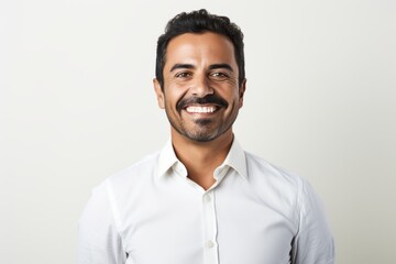 Portrait of handsome Indian man with white shirt smiling at camera.