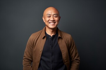 Fototapeta premium Portrait of a happy mature asian man smiling against grey background