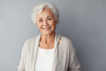 Fototapeta premium Portrait of a happy senior woman smiling at the camera over grey background