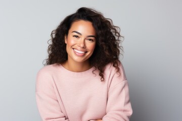Fototapeta premium Portrait of a smiling young woman with curly hair over gray background