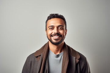 Obraz premium Portrait of a handsome young man smiling at the camera while standing against grey background