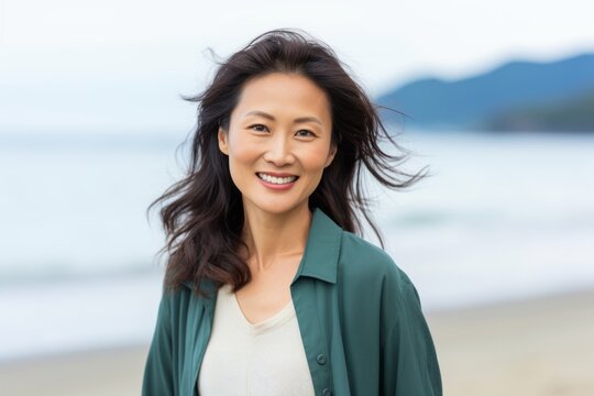 Portrait of smiling asian woman standing on beach at seaside