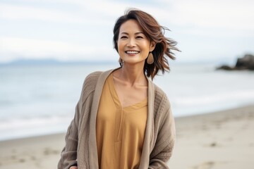 Portrait of a smiling asian woman standing on the beach with her arms crossed