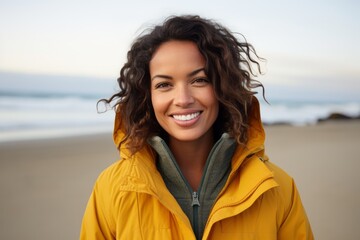 Close up portrait of a smiling young woman standing on the beach looking at camera