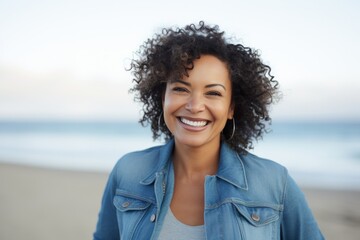 Portrait of a smiling young woman with curly hair standing on the beach