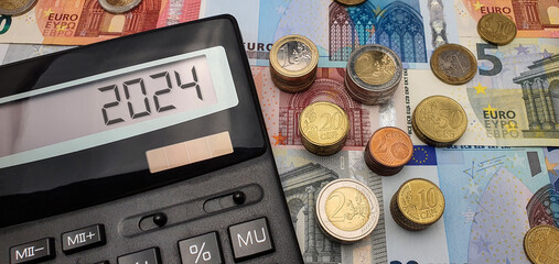 Promising prospects for euro strengthening in 2024. An abundance of banknotes, coins and a calculator symbolize financial growth. The calculator screen displays the year 2024 - obrazy, fototapety, plakaty