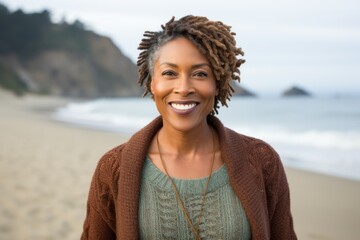 Portrait of a smiling young woman standing on the beach at sunset