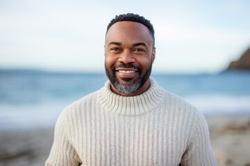 Portrait of smiling man standing on beach with ocean in the background
