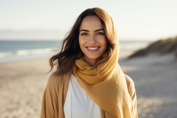 Portrait of a smiling young woman in yellow scarf on the beach