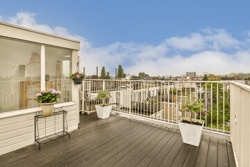 a balcony with white railings and potted planters on the side of the deck, looking out to the city