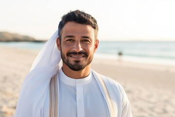 Portrait of handsome arabian man smiling at camera on the beach