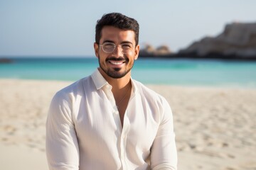 Fototapeta na wymiar Portrait of a handsome young man standing on the beach and smiling