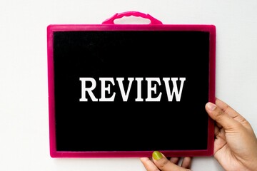 Review text or word written on blackboard or  black chalkboard held with hand in white background.