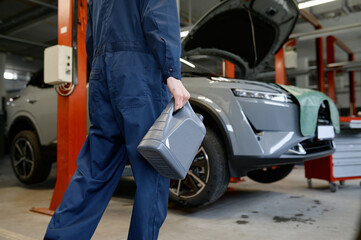 Closeup auto mechanic carrying bottle of oil for change