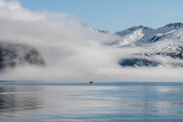 Obraz na płótnie Canvas Boat approaching fog on the mountains and sea in Passage Canal, Whittier, Alaska USA