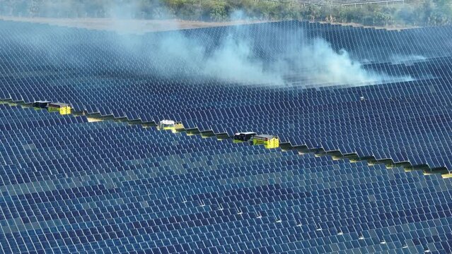 View from above of wildfire between photovoltaic power plant with many rows of solar panels for producing clean electrical energy. Concept of natural disaster at critical facility