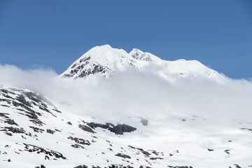 Fototapeta na wymiar Sun and shadows on a snow covered mountain with clouds and mist, Alaska, USA
