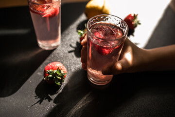 Strawberry soda delight. A sweet and tangy summer drink served in a glass with ice cubes. pink color and fresh strawberry slices