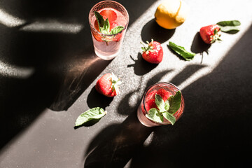 Berrylicious strawberry mojito. tropical twist on classic cocktail. Fresh strawberries, lime, and mint leaves combine to create vibrant and flavorful drink. Served over ice in glass on dark background