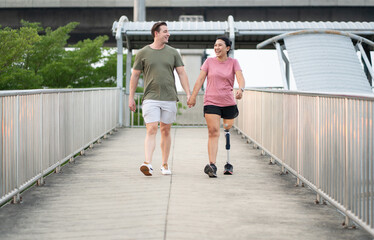 Exercise Asia woman with prosthetic leg holding hand caucasian boy friend in the park city	