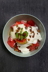 Greek yoghurt in a bowl with fruit slices and honey