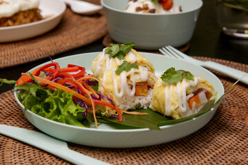 Special egg rolls with rice and salmon served with fresh vegetable salad on the restaurant table