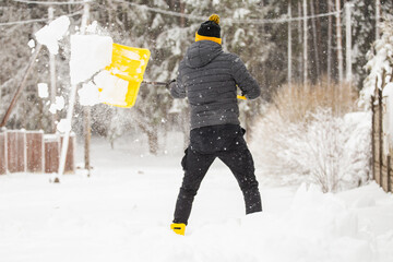 A man frees the passage after a heavy snowfall - rakes a snowdrift with a shovel in winter