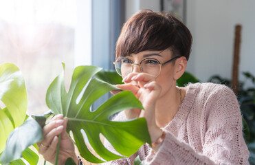 Woman checking her home plants for diseases and pests