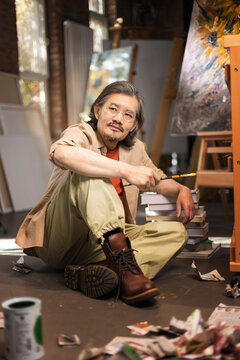 A veteran painter who sits on the ground in his studio and paints
