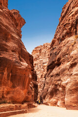 Tourists in narrow passage of rocks of Petra canyon in Jordan. Petra has been a UNESCO World Heritage Site since 1985. Way through Siq gorge to stone city Petra