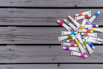 Background blank white canvas with tubes of colored paints on wooden