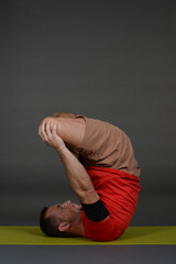 Man doing yoga in photo studio on isolated background.	