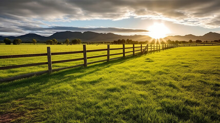 Green grass field, wooden Fence and mountain on horizon at summer morning. American spring sunrise. Generative AI