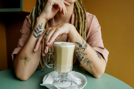 Young woman sits in cafe and drinks cappuccino.