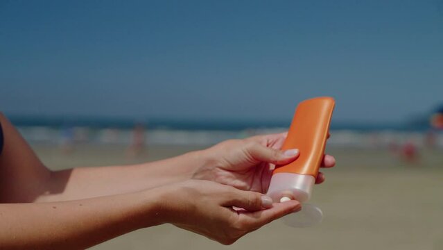 Close-up woman takes sunscreen of tube, moisturizing lotion applies sunblock on her hands.
