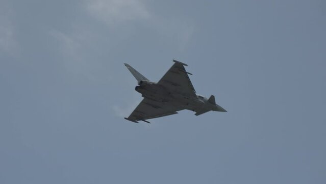 Fast fighter jet during high speed combat maneuvers with clouds