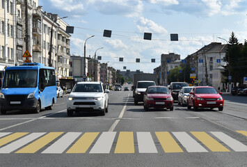 Central street of the city. Cars stopped at a traffic light in front of a pedestrian crossing.