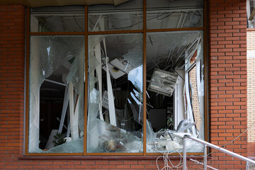 Broken windows of civilian building of bomb explosion. Shards of glass stick out dangerously in...