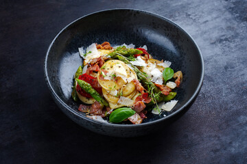 Green glazed asparagus with fried prosciutto ham, croxetti pasta and parmesan cheese served as close-up on a design plate with text space