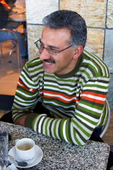 smiling arab man relaxing after work having a coffee on a terrace