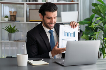 Professional businessman in black suit, present financial data or BI paper via laptop during online...