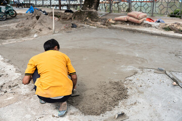 Asian man in yellow shirt at work laying concrete